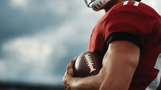 Football Player Ready for Action. Quarterback with focus and determination to dominate the game. Red jersey, helmet, and holding the ball. Cloudy backdrop.