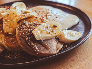 chocolate pancakes with banana slices and caramel on a dark plate