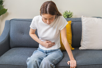 Sick asian young woman in pain, hand holding belly, stomach pain from food poisoning, girl hurt abdomen ache and digestive problem, gastritis or diarrhea. Health care inflammation, abdominal problem