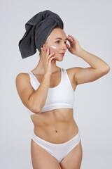 A young beautiful girl in white lingerie with a towel on her head does cosmetic procedures.