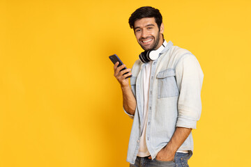 Happy Man using mobile phone isolated on yellow background