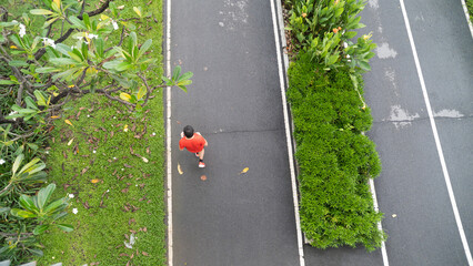 Aerial view of a person jogging on a path in a park with lush greenery