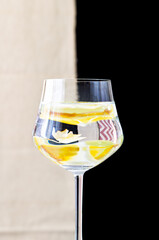 Glasses of water with a reflected yellow orchid. Beige and black background.