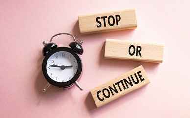 Stop or Continue symbol. Concept words Stop or Continue on wooden blocks. Beautiful pink background...