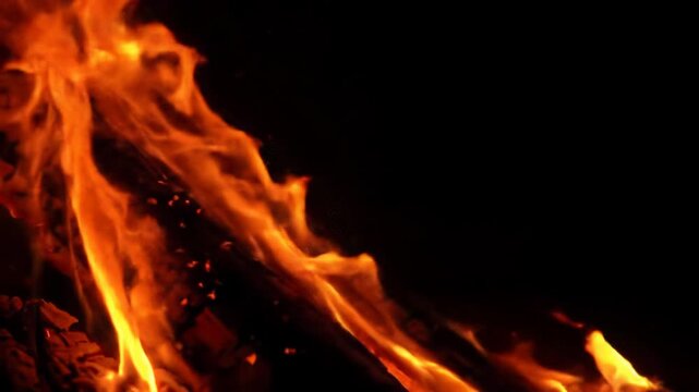 Close-up video of incandescent fiery orange and crimson liquid fire tendrils erupting explosively and flowing against an absolute black void, with glowing embers and smoke dissipating downwards.