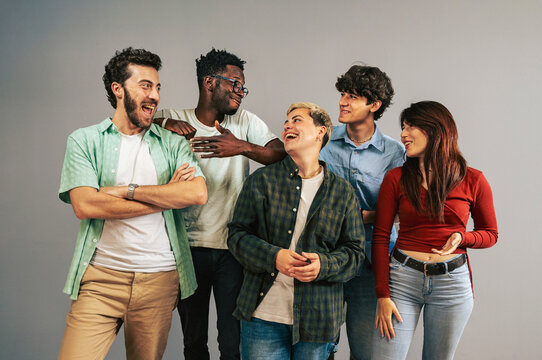 Group of diverse young friends laughing together in a studio portrait showing multi-ethnic gen z people having fun. Concept of authentic community, teamwork, friendship, inclusion for a new generation