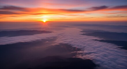 Fototapeta premium Sunrise over fog-filled valley, mountains, with bright, warm light