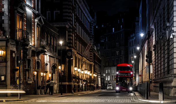 Classic London red bus navigates through a brightly lit street with Christmas decorations and busy foot traffic. Ideal for travel, holiday, or urban lifestyle themes.