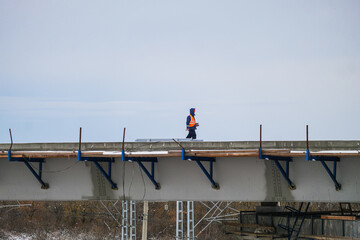 Naklejka premium Construction workers in orange vests are busy constructing a bridge or road