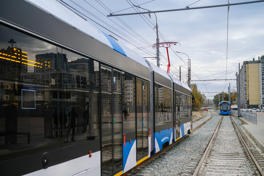 A modern tram moving along the tram tracks in the city. The second tram is approaching along parallel tracks