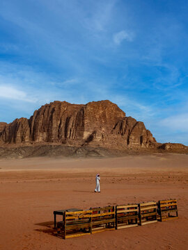 A lone beduin against a Desert landscape in the Wadi Rum of Jordan and a rocky mountain
