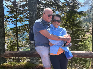 Happy couple of seniors embracing in outdoors excursion in mountain - active pensioners enjoying nature and healthy lifestyle on a sunny day