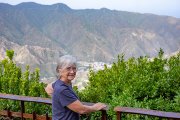 Senior caucasian woman on hiking trip with backpack on shoulders enjoying freedom and nature. Elderly active woman on a leisure trip, healthy lifestyle in retirement