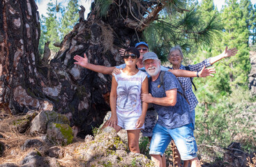 Cheerful group of senior people looking at camera while enjoying a mountain hike in the forest appreciating leisure and freedom, happy retired seniors and healthy lifestyle concept