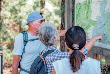 Group of senior friends in outdoors excursion looking at the map looking for right direction in the mountain area