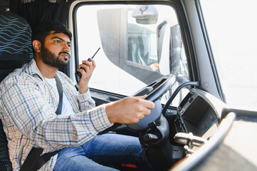 Truck driver communicating using walkie talkie while driving