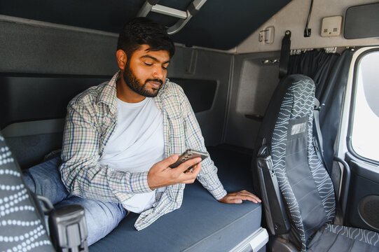 Indian truck driver resting using smartphone in cabin