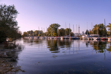 Serene view of Ward's Island Marina at sunset, capturing the peacefulness of moored sailboats against the Toronto skyline.