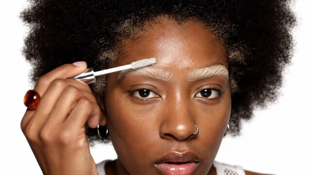 Black woman with blonde bleached eyebrows applying clear brow gel with a brush, closeup portrait vector illustration