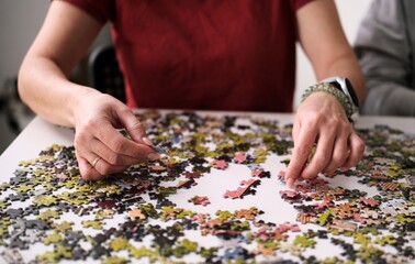 Woman's Hands Putting A Puzzle Together On The Table, A Hobby For The Whole Family