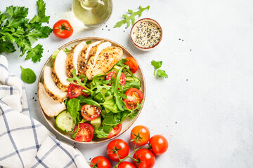 Healthy food. Green salad with grilled chicken meat at white table. Top view.