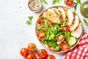 Chicken salad with grilled chicken breast and fresh vegetables at white kitchen table. Top view.