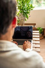 vertical Young Hispanic man teleworking from home using laptop