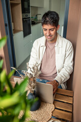 vertical Young Hispanic man teleworking from home using laptop