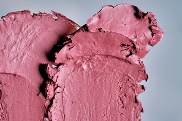The texture of red lipstick on glass on a neutral background.