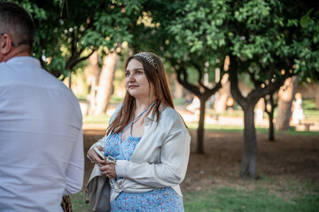 Woman in light blue floral dress standing in green park on sunny day