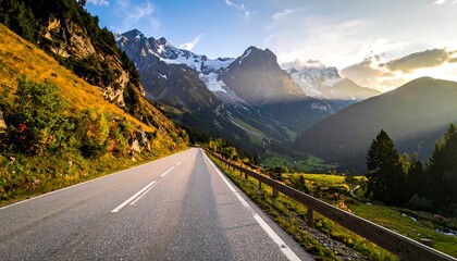 A long asphalt road stretches towards snow-capped mountains under a partly cloudy sky with golden sunlight and surrounding greenery