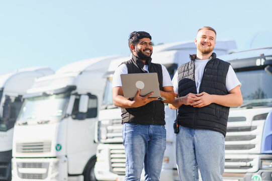 Logistics team men working with laptop near trucks