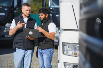 Truck drivers discussing logistics, using laptop
