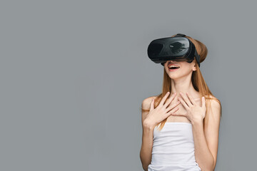 Young caucasian female experiencing virtual reality with headset on grey background.