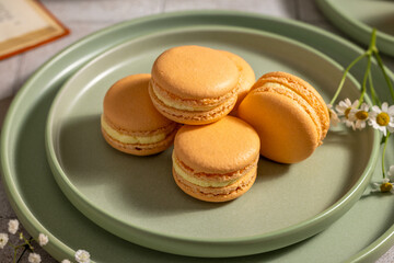 Stack of orange macarons on sage green plates