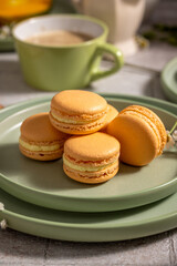 Orange macarons on green plate with coffee