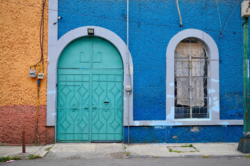 Close-Up of Arched Teal Double Door With Geometric Patterns Against Blue and Orange Walls (Mexico City, Mexico)