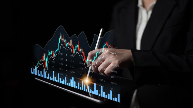 A businessman reviews stock market trends using a tablet with digital graphs in a dark office, highlighting the significance of data analysis in investment decisions. Scalp