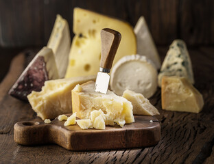 Parmesan cheese and assorted cheese plate on rustic wooden board.