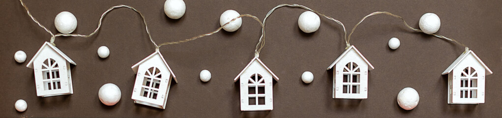 Image with white houses on a brown background, snowflakes round, Christmas. Christmas banner for decorating web pages and websites, holiday houses garlands with windows