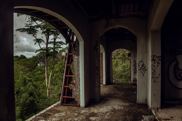 A beautiful abandoned hotel in the jungle. Dilapidated walls, cloudy sky. Green trees near the abandoned hotel.