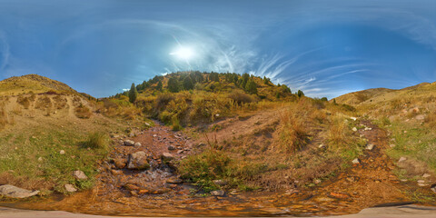 Full Spherical 360 degrees tone-mapped HDRi panorama of small mountain creek in autumnal valley between yellow foothills at sunny day in equirectangular projection