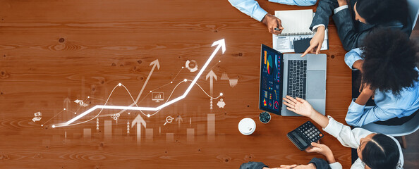 A team of professionals engages in collaborative analysis of financial data, showcasing various graphs and charts on a laptop screen in a modern office environment. Trope