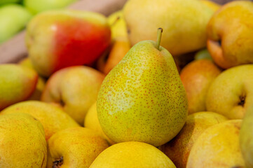 A pile of ripe juicy yellow pears displayed for sale on a supermarket vegetable counter. Demonstration of organic vegetarian and healthy food. Close-up