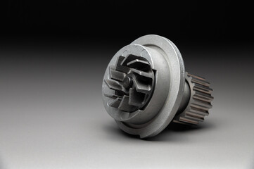 A new, shiny aluminum engine coolant pump on a gray gradient background. Contrast backlighting.