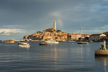 A spectacular sunrise in Rovinj, Croatia. The colorful houses of the old town are beautifully illuminated by the rising sun. A rainbow over the Adriatic resort.