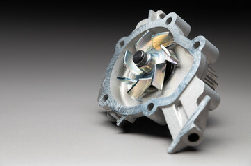 A water pump for a car's cooling system on a black gradient background. The water pump circulates coolant through the engine block. The car parts are new.