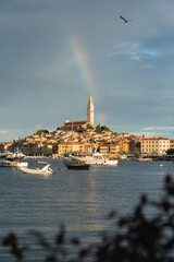 A spectacular sunrise in Rovinj, Croatia. The colorful houses of the old town are beautifully illuminated by the rising sun. A rainbow over the Adriatic resort. Vertical view
