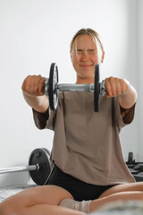 Young Gen Z woman doing barbell workout at home. Concept of mindful fitness, wellness, self-care,...
