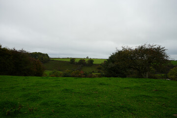 Obraz premium Overcast sky above rolling green hills and autumn trees in the scenic countryside of Crich Derbyshire England
